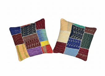 Two patchwork-style pillows with colorful patterns on a white background