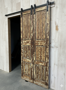  Wooden sliding barn door with rustic design on a light wooden wall.