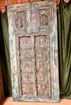 Vintage wooden door with intricate carvings against a green curtain background