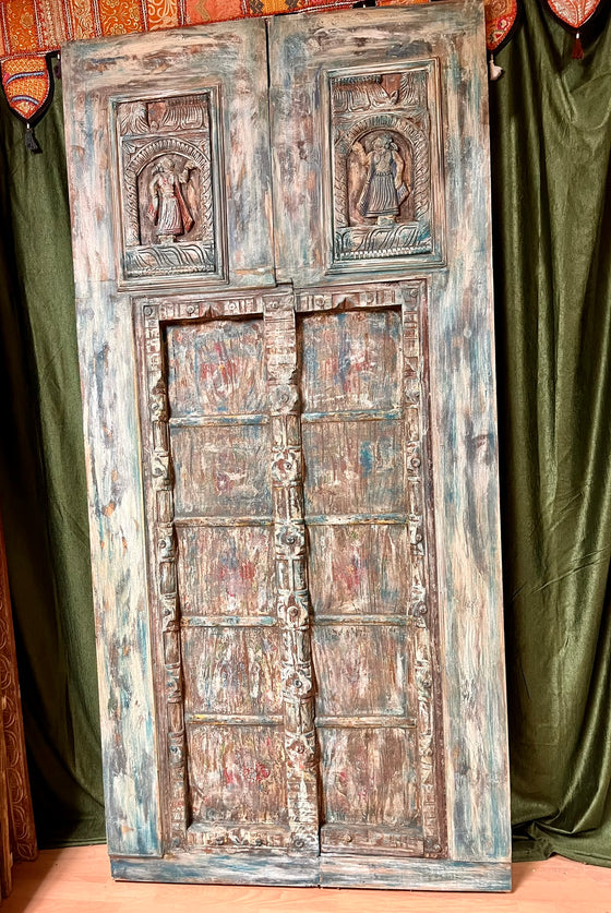 Vintage wooden door with intricate carvings against a green curtain background