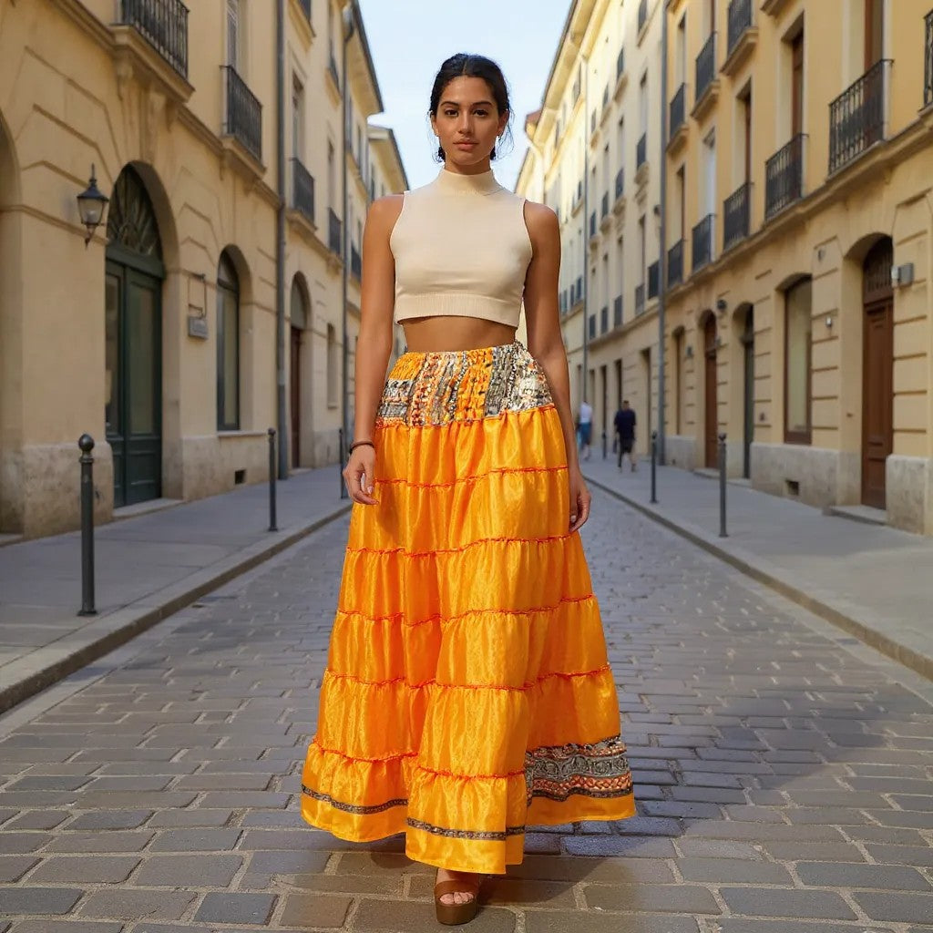  Woman wearing a beige top and bright orange skirt on a sunlit street.