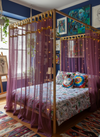 Bedroom with a canopy bed, colorful bedding, and decorative pillows.