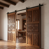 Wooden sliding doors with decorative carvings in a room with a desk and bookshelf.