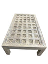 Wooden coffee table with decorative grid pattern on a concrete floor